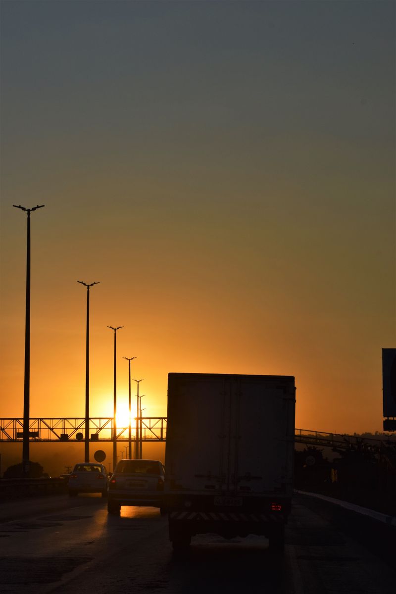 Rodovia brasileira ao entardecer com veículos em movimento